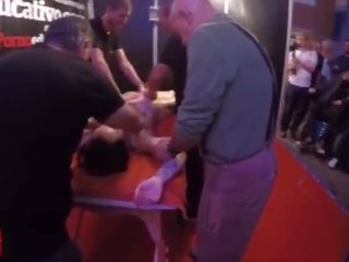 A group of people massage this young and tattoed lady at the same time in public